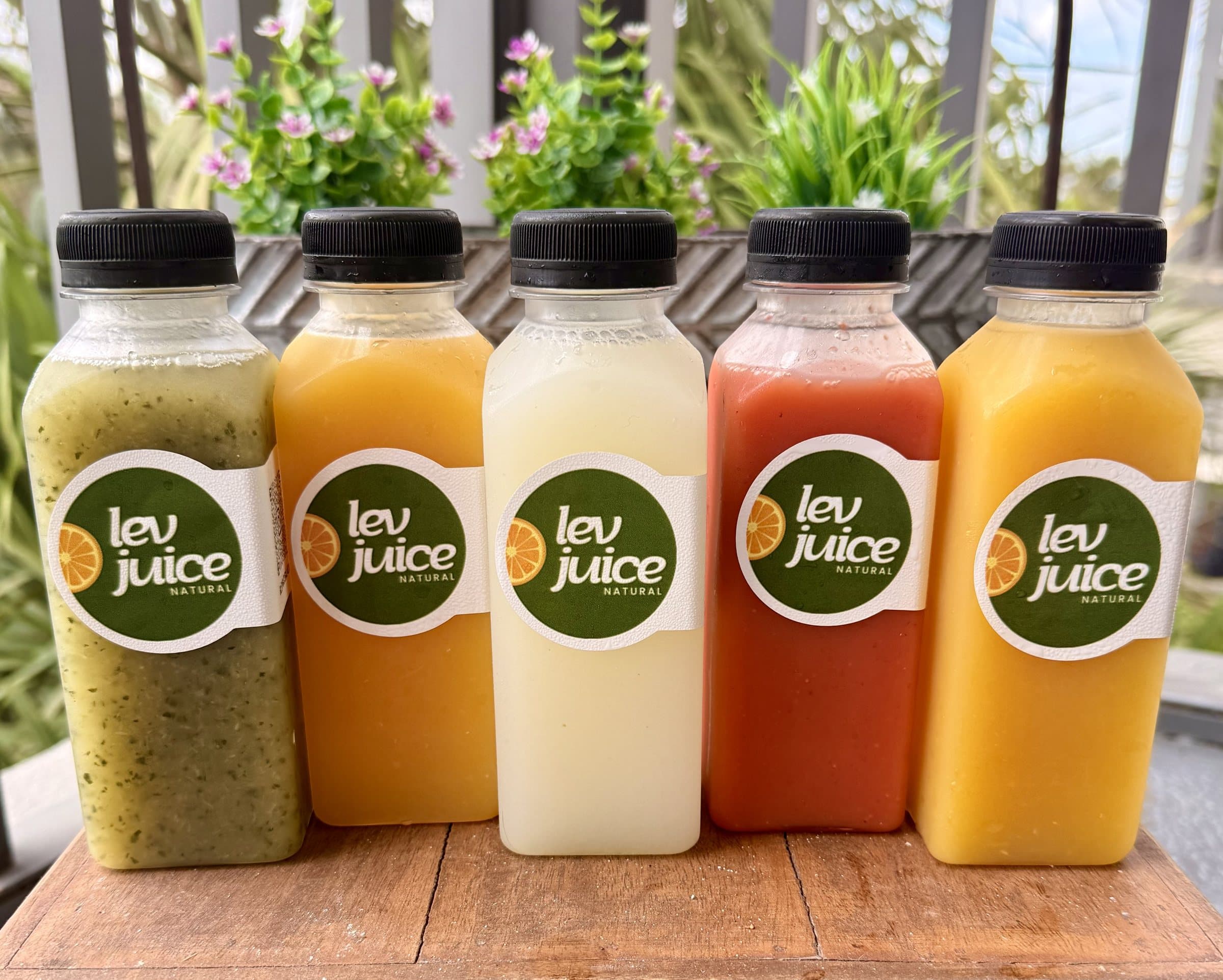 Five bottles of LEV juice in green, orange, white, red and yellow