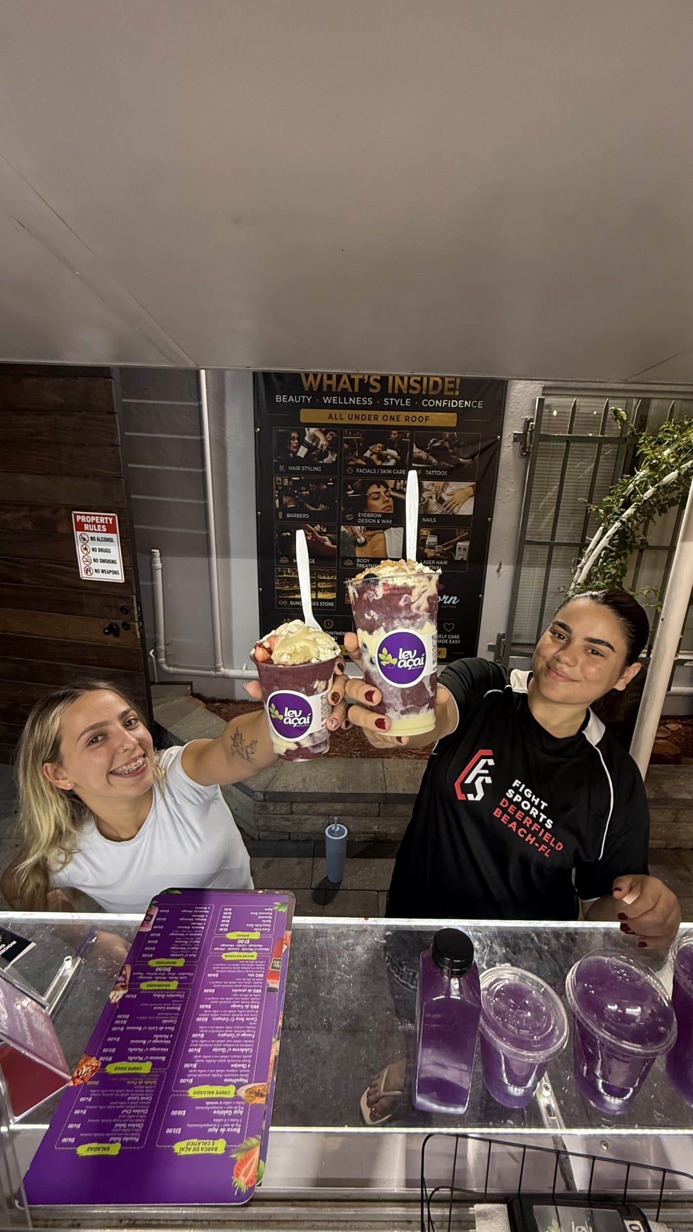 Two LEV team members smiling and handing açaí cups through the truck window